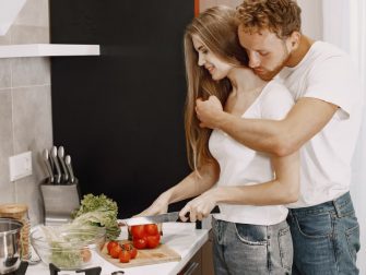 A loving couple enjoys cooking fresh vegetables together in a cozy, modern kitchen setting.
